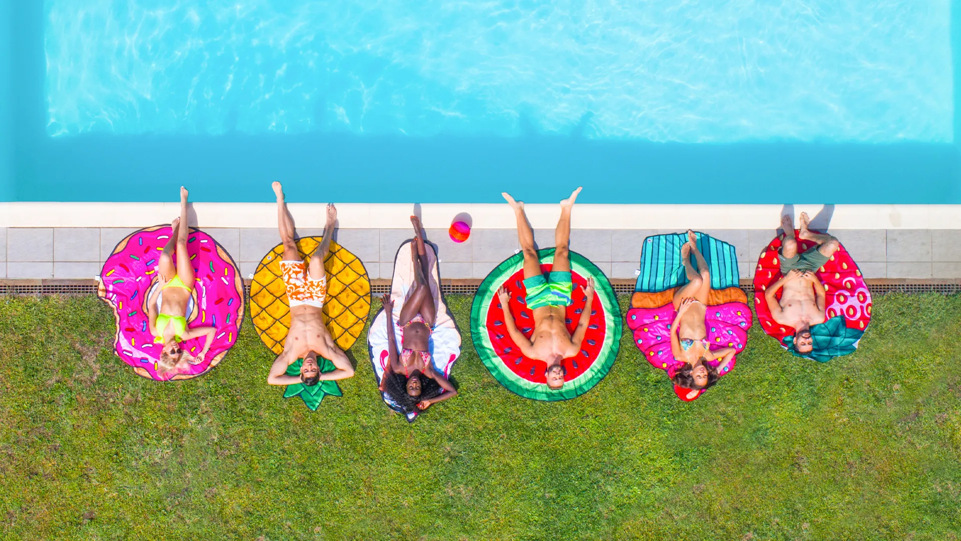 Aerial view of friends relaxing on colorful pool floats beside the pool at Hotel NYX Cancun.