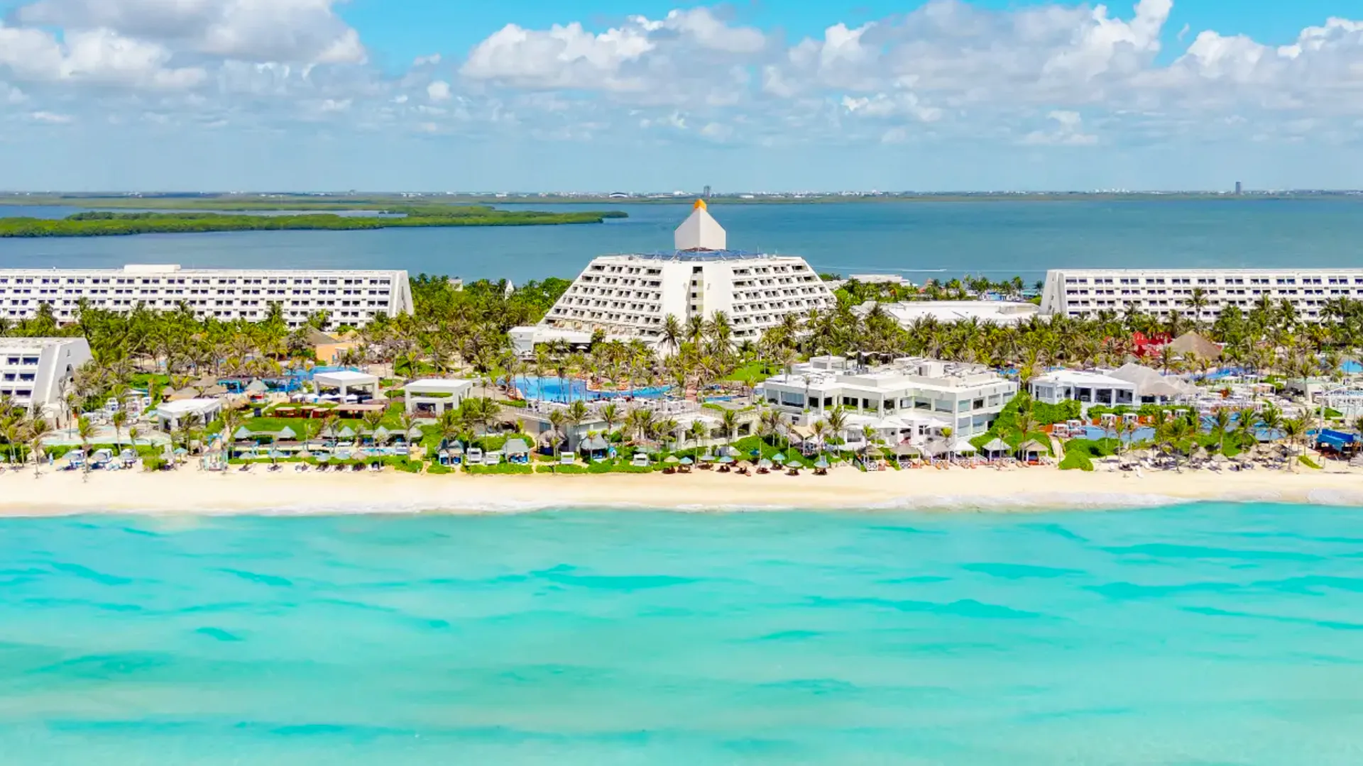  A stunning aerial view of Grand Oasis Cancun, showcasing its beautiful beachfront and lush landscaping, offering a perfect getaway with crystal-clear waters and resort amenities.