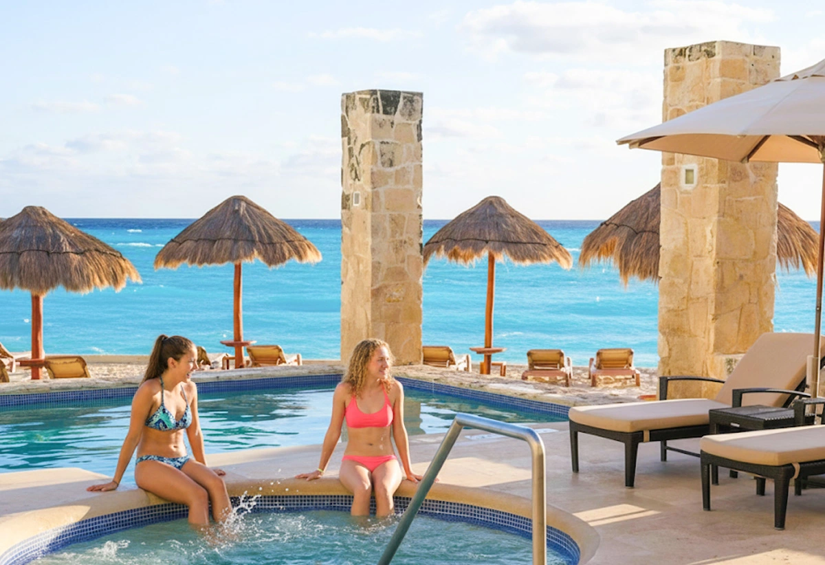 Guests relaxing in a beachfront jacuzzi surrounded by palapas and lounge chairs at The Westin Cancun.