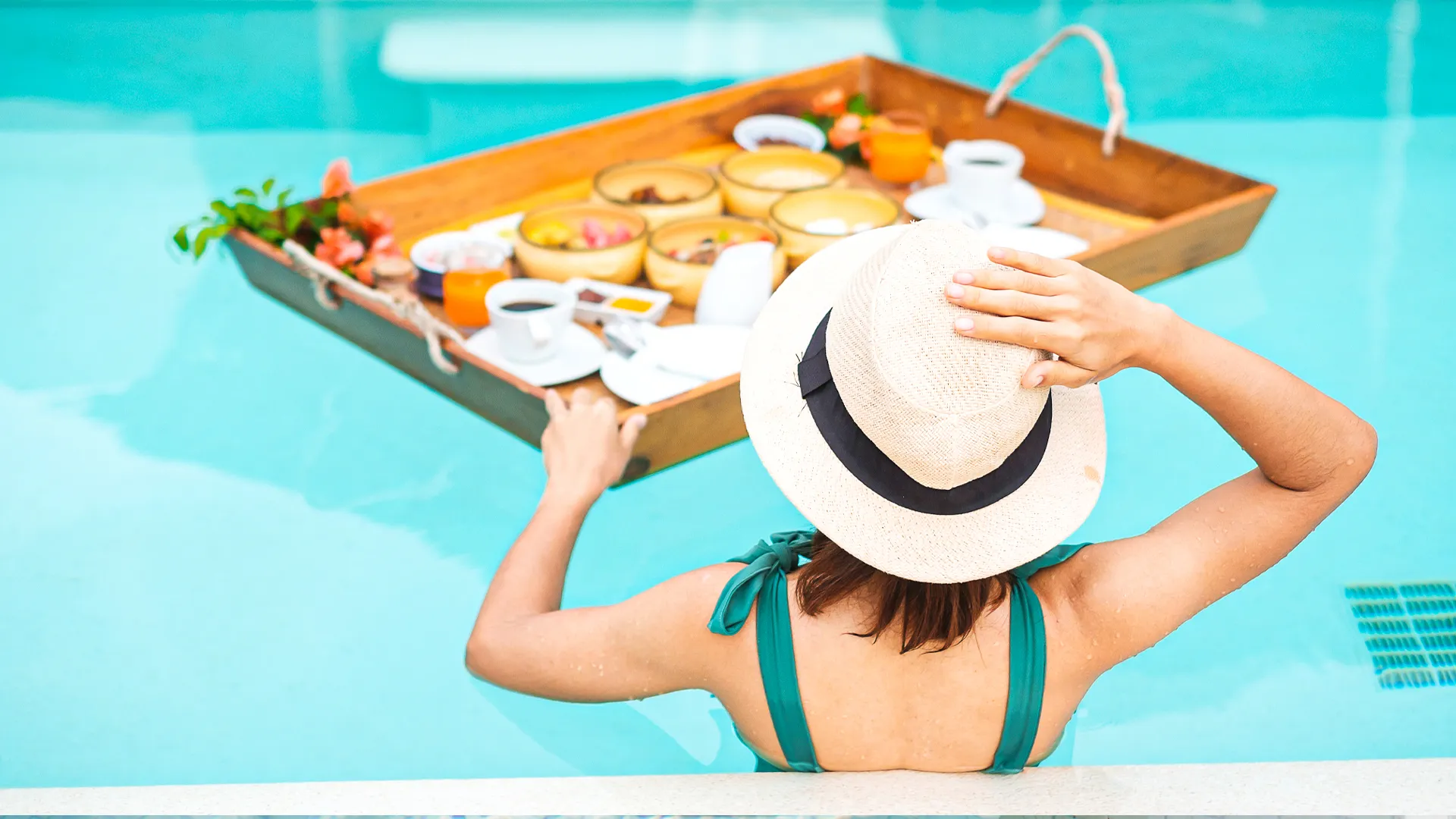 Woman in a sunhat enjoying a floating breakfast tray in the pool at Riu Palace Las Americas, Cancun.