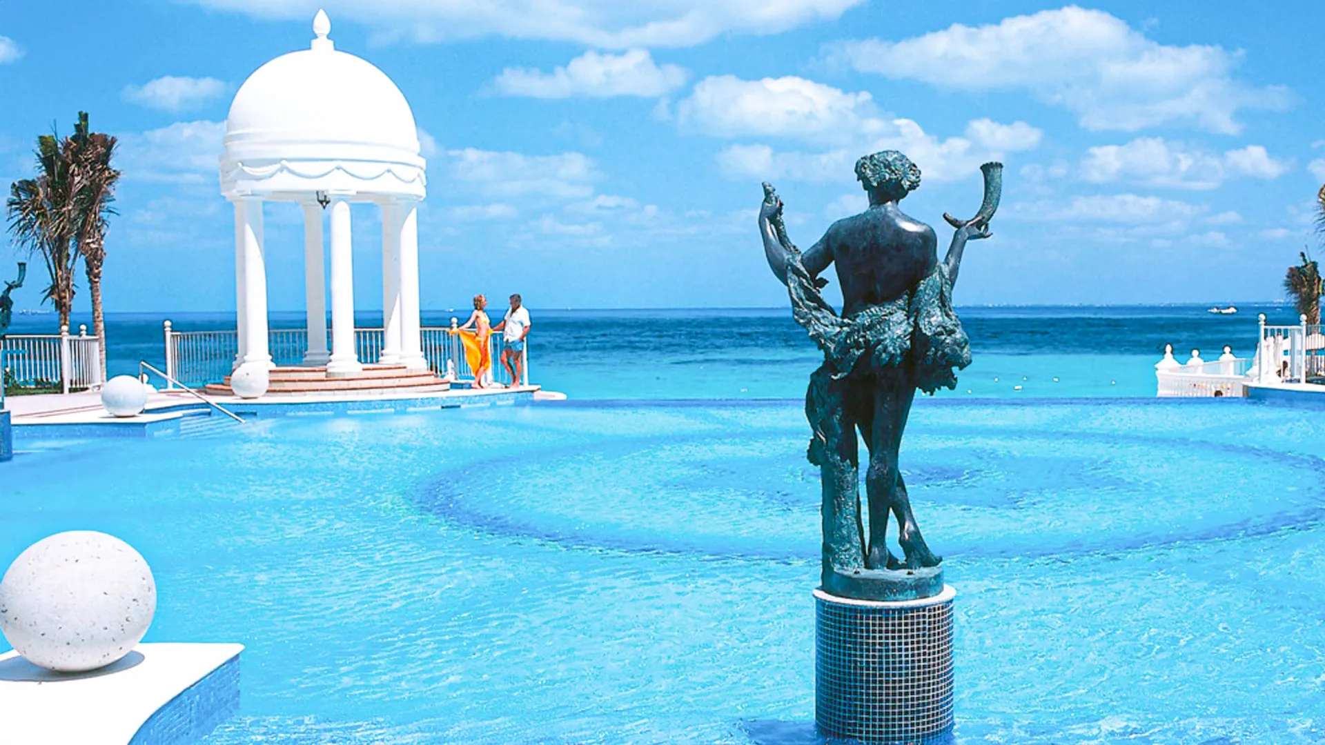  Oceanfront pool with a classical bronze statue and white domed gazebo at Riu Palace Cancun. 