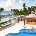 Panoramic view of Excellence Cancun’s beachfront pool area with cabanas and sun loungers.