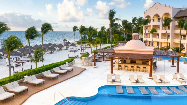 Panoramic view of Excellence Cancun’s beachfront pool area with cabanas and sun loungers.
