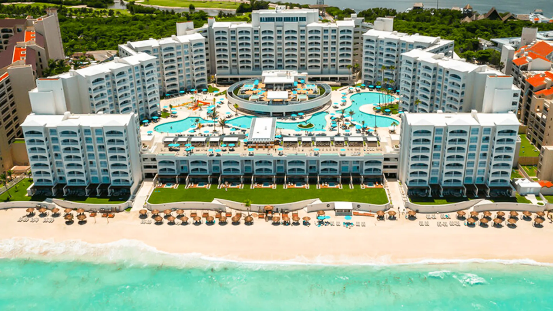 Aerial view of Hilton Cancun resort with pools, beachfront cabanas, and turquoise Caribbean waters.