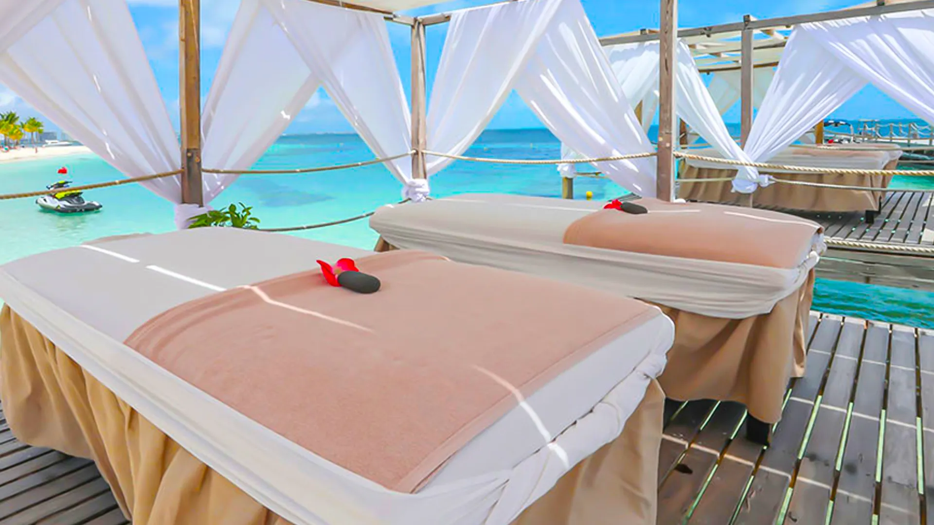 Outdoor spa cabanas by the beach with massage tables overlooking turquoise waters at Riu Palace Las Americas Cancun.