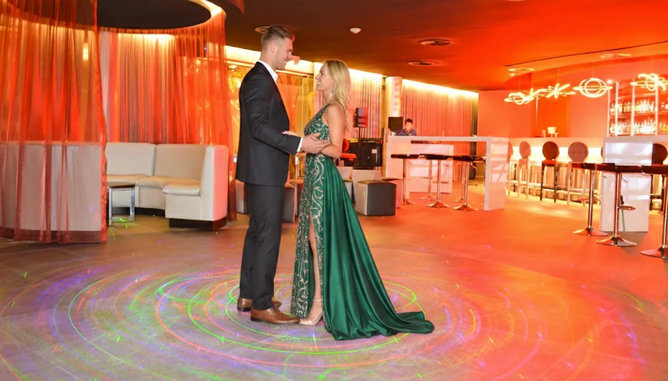 Couple dressed elegantly dancing together inside Royalton Riviera Cancun’s modern bar lounge with warm ambient lighting.
