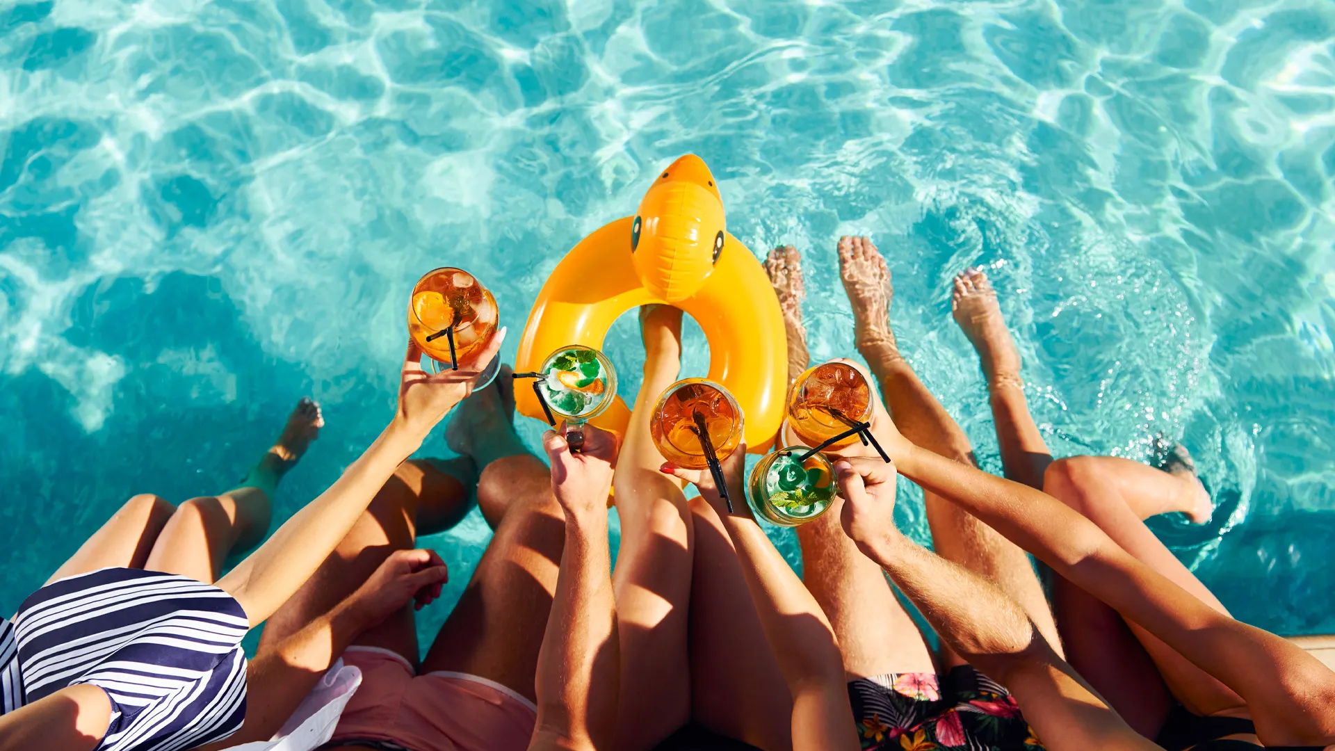 Group of friends relaxing at the pool with colorful cocktails at Breathless Riviera Cancun Resort.