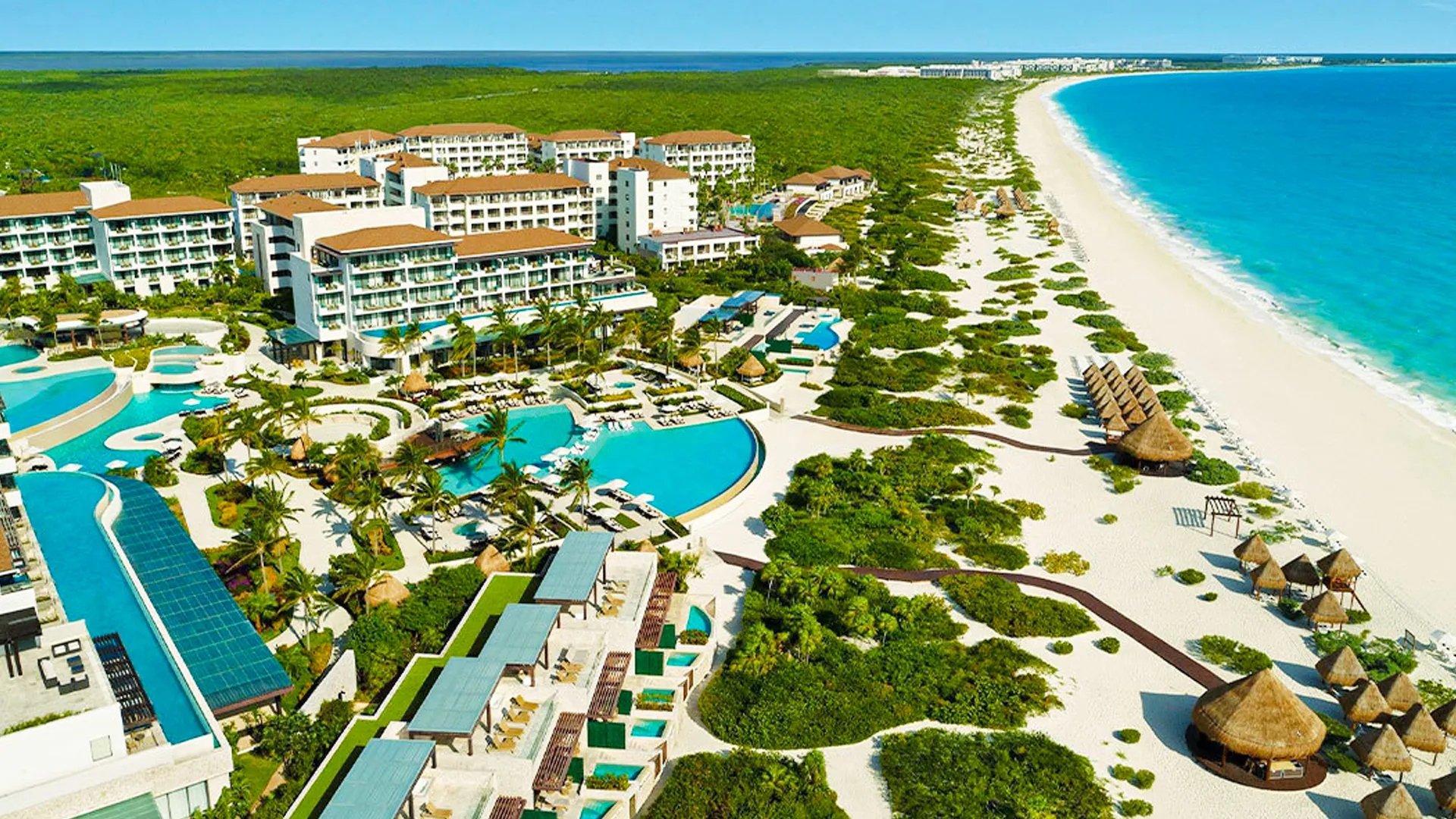Aerial view of Secrets Playa Mujeres resort in Cancun with pools, beachfront, and tropical greenery.