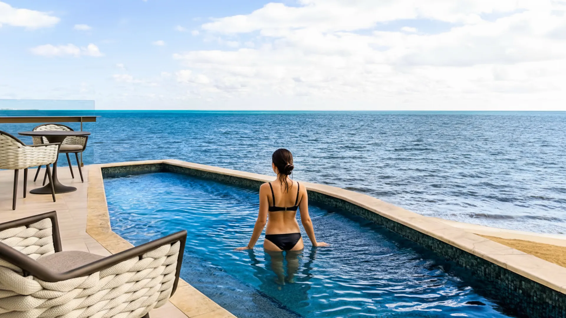 Woman in a bikini relaxing in a private oceanfront plunge pool at Hilton Cancun.