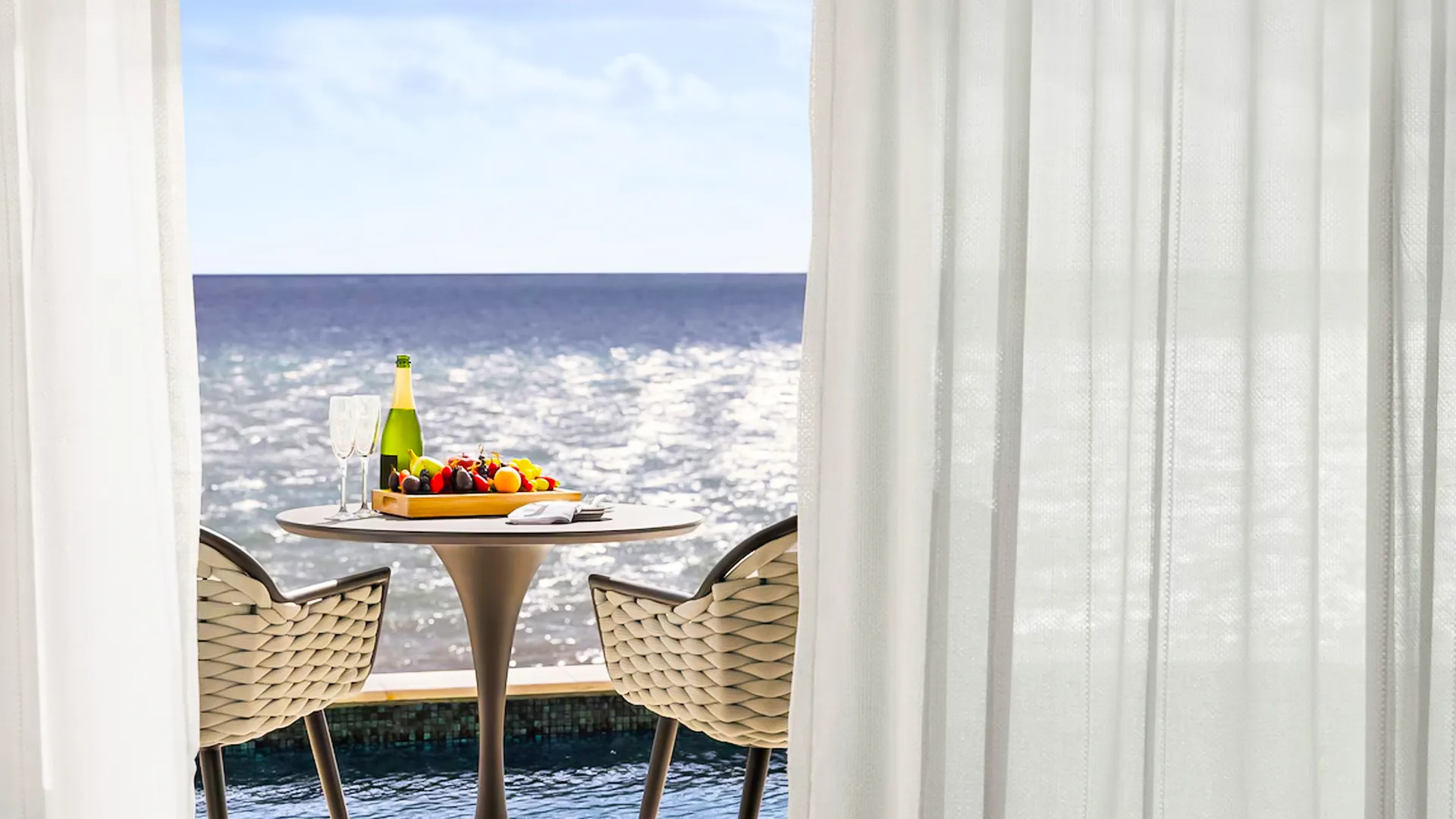 Ocean-view breakfast setup on a private balcony at Hilton Cancun with champagne and fresh fruit.