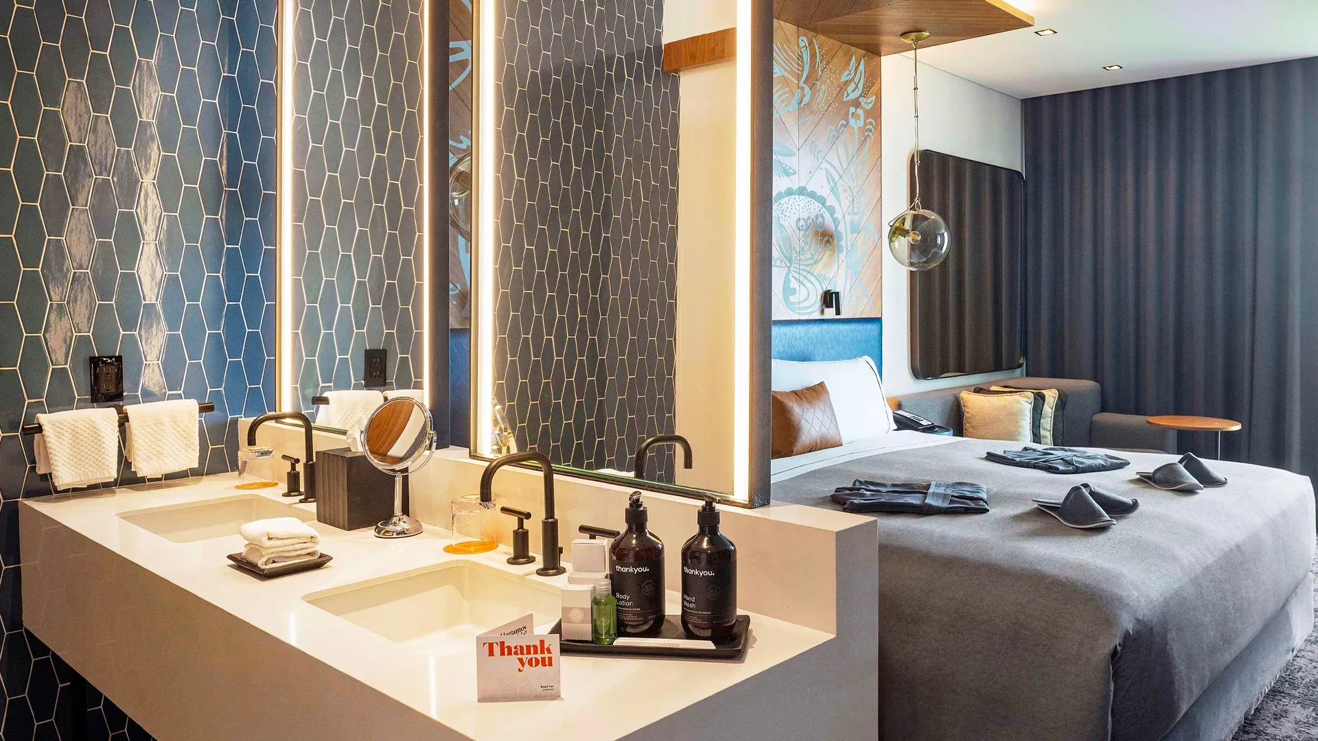 Modern hotel suite at Hilton Cancun with stylish decor, double vanity, and cozy bedding.