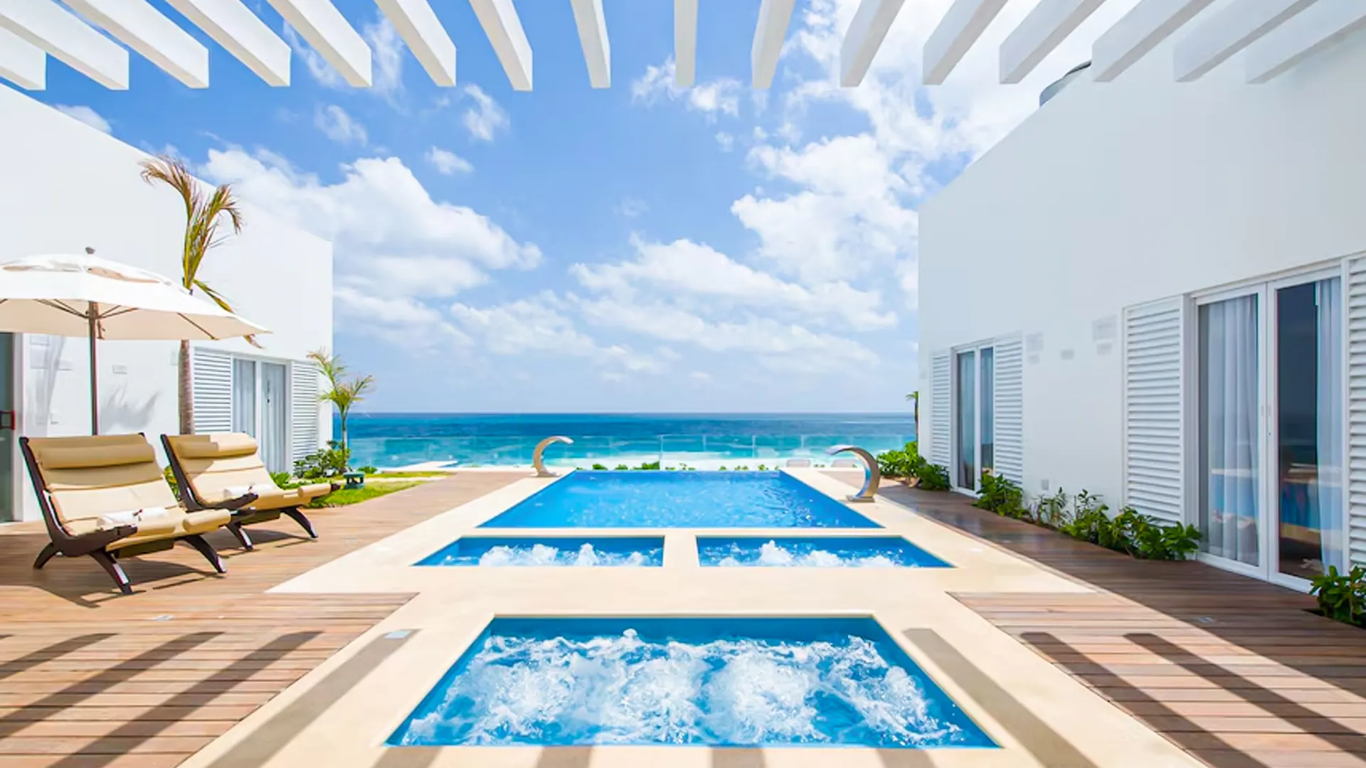 Private outdoor pool area at Oleo Cancun Playa with jacuzzis, lounge chairs, and direct ocean views.