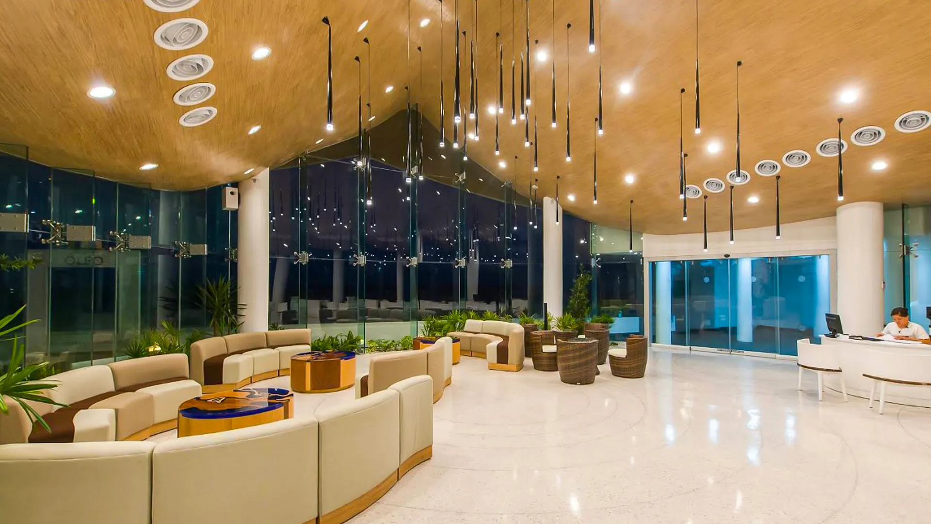 Contemporary lobby at Oleo Cancun Playa with curved seating, warm lighting, and sleek modern décor.