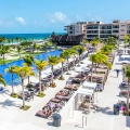 Main pool area at Royalton Splash Riviera Cancun with sun loungers, palm trees, and ocean backdrop.