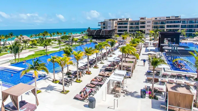 Main pool area at Royalton Splash Riviera Cancun with sun loungers, palm trees, and ocean backdrop.