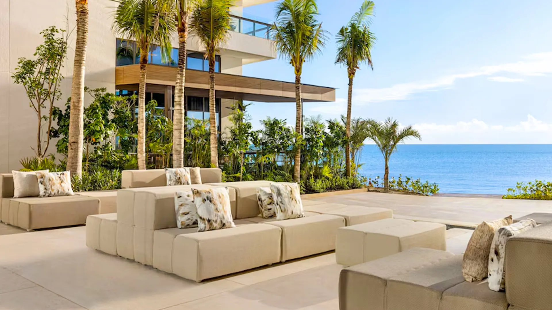 Modern ocean-view terrace with palm trees and lounge seating at Hilton Cancun resort.