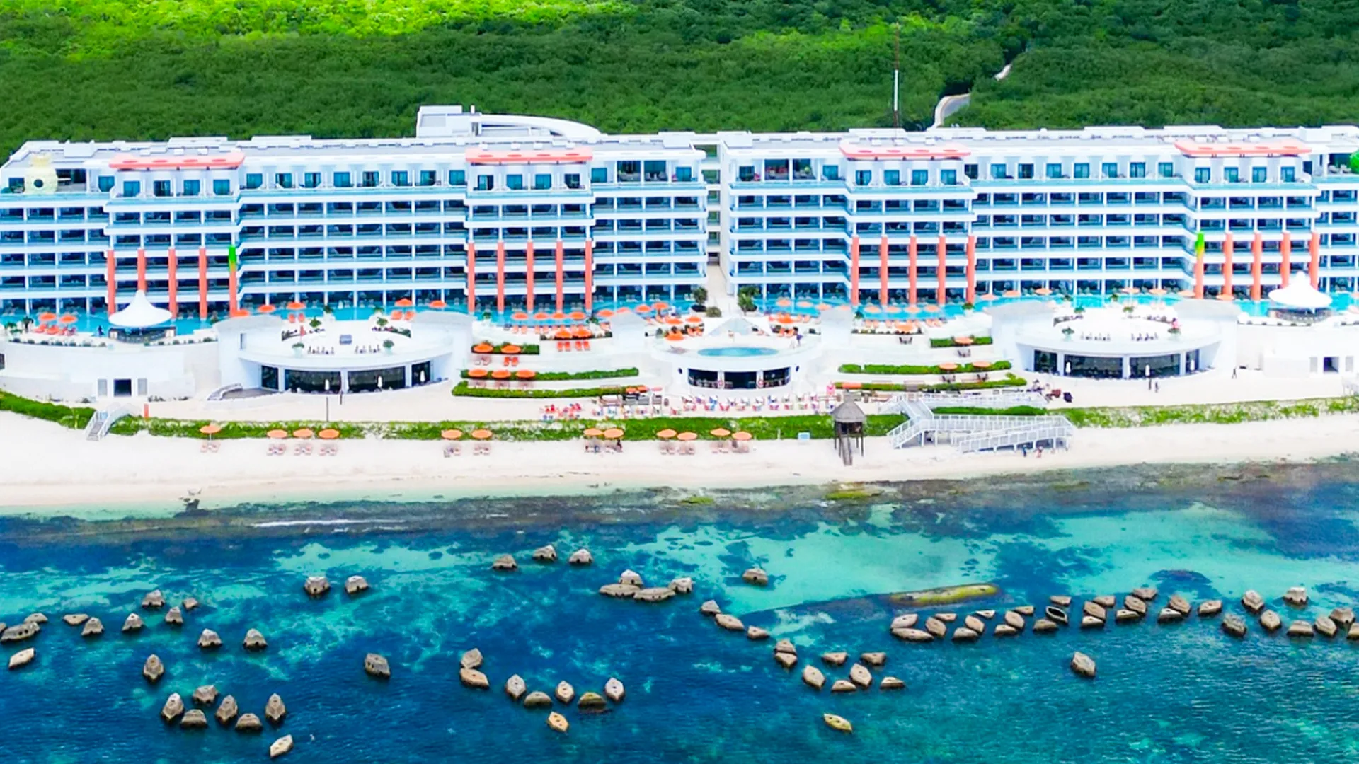 Aerial view of Nickelodeon Resort Cancun showing the beachfront suites, infinity pools, and turquoise Caribbean Sea.