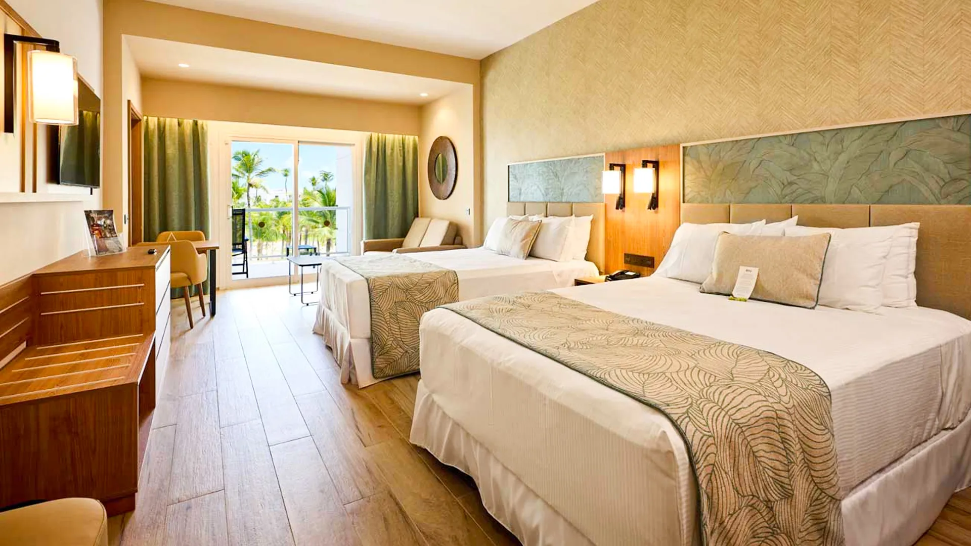  Modern double room at Riu Palace Cancun with two queen beds, tropical décor, and balcony view of palm trees. 
