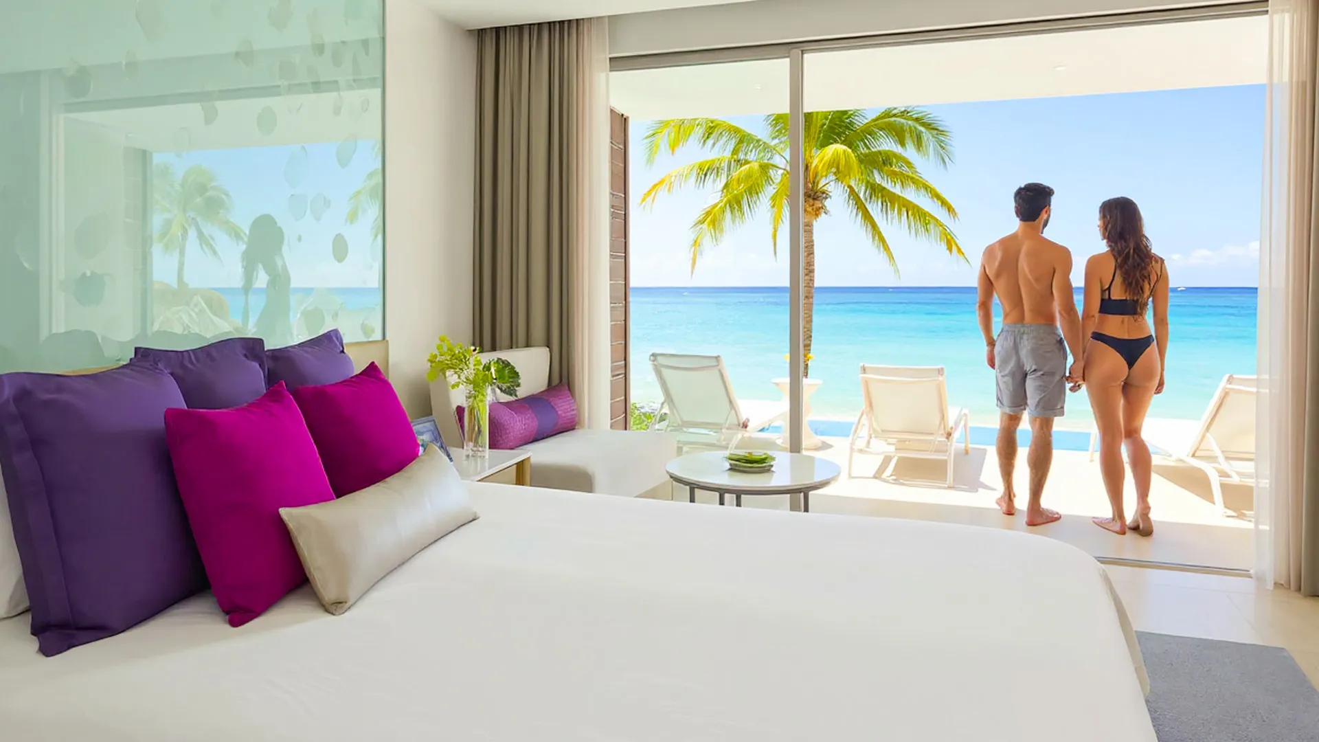 Couple enjoying the oceanfront view from their suite at Breathless Riviera Cancun Resort.