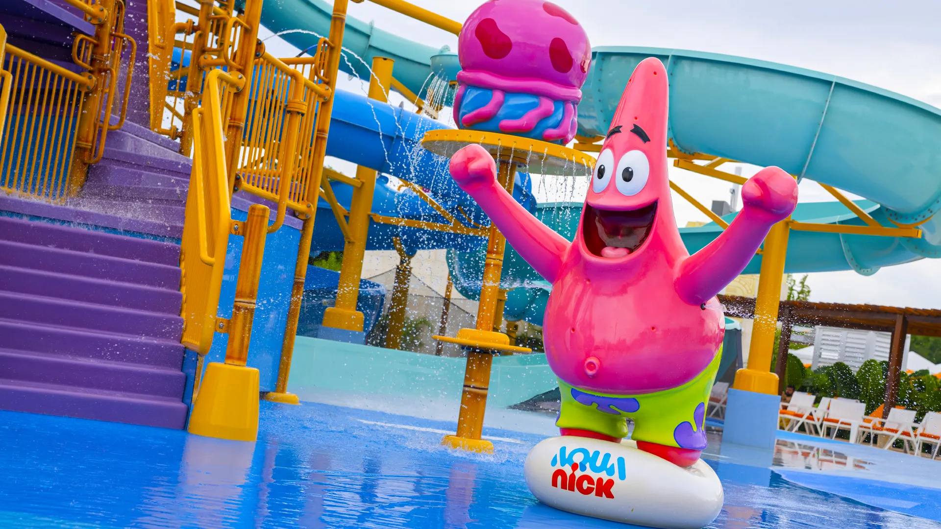  Patrick Star statue at Aqua Nick waterpark in Nickelodeon Resort Cancun, surrounded by colorful slides and splashing jellyfish fountains. 