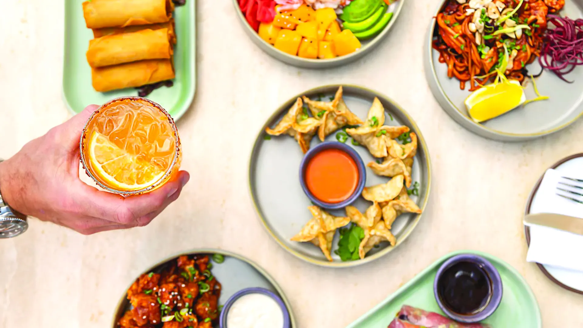 Colorful Asian-fusion dishes and a refreshing cocktail served at Hilton Cancun restaurant.