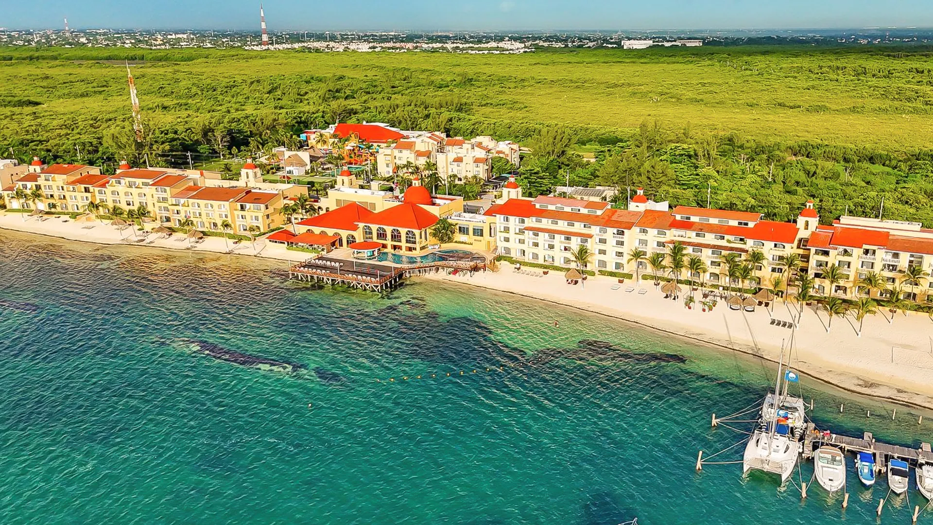 Aerial view of All Ritmo Cancun Resort & Waterpark along the beach with turquoise Caribbean waters and marina.