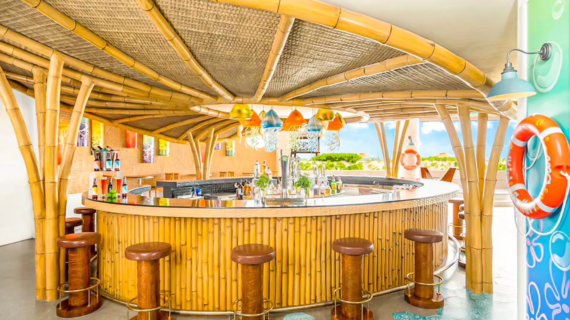 Tropical bamboo-style swim-up bar at Nickelodeon Resort Cancun with colorful hanging lights and ocean breeze views. 