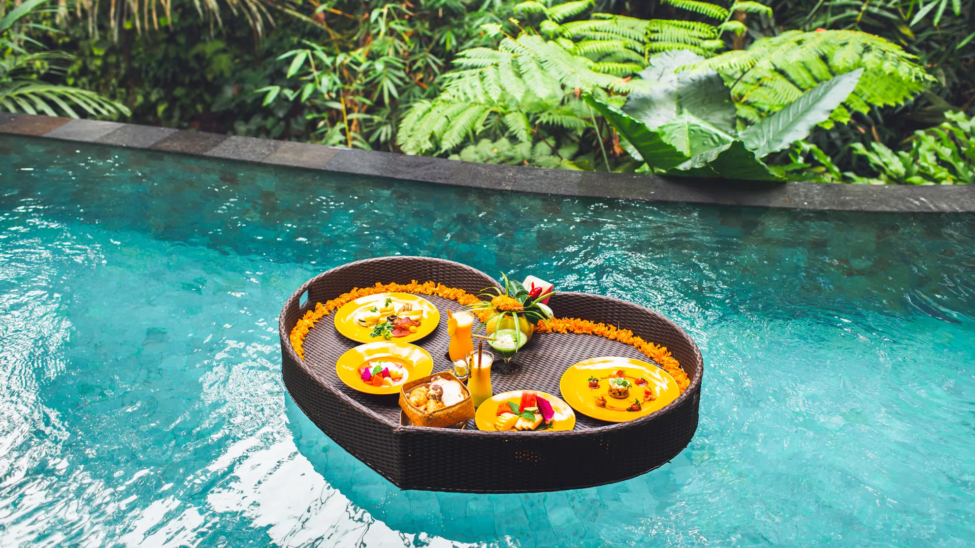 Heart-shaped floating breakfast tray with tropical fruits and juices at Breathless Riviera Cancun Resort.