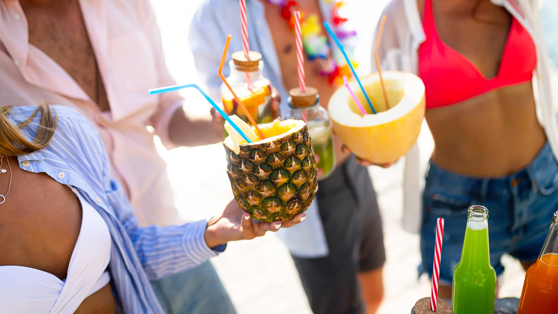 Guests enjoying tropical drinks served in fruit shells at Oleo Cancun Playa beach party.