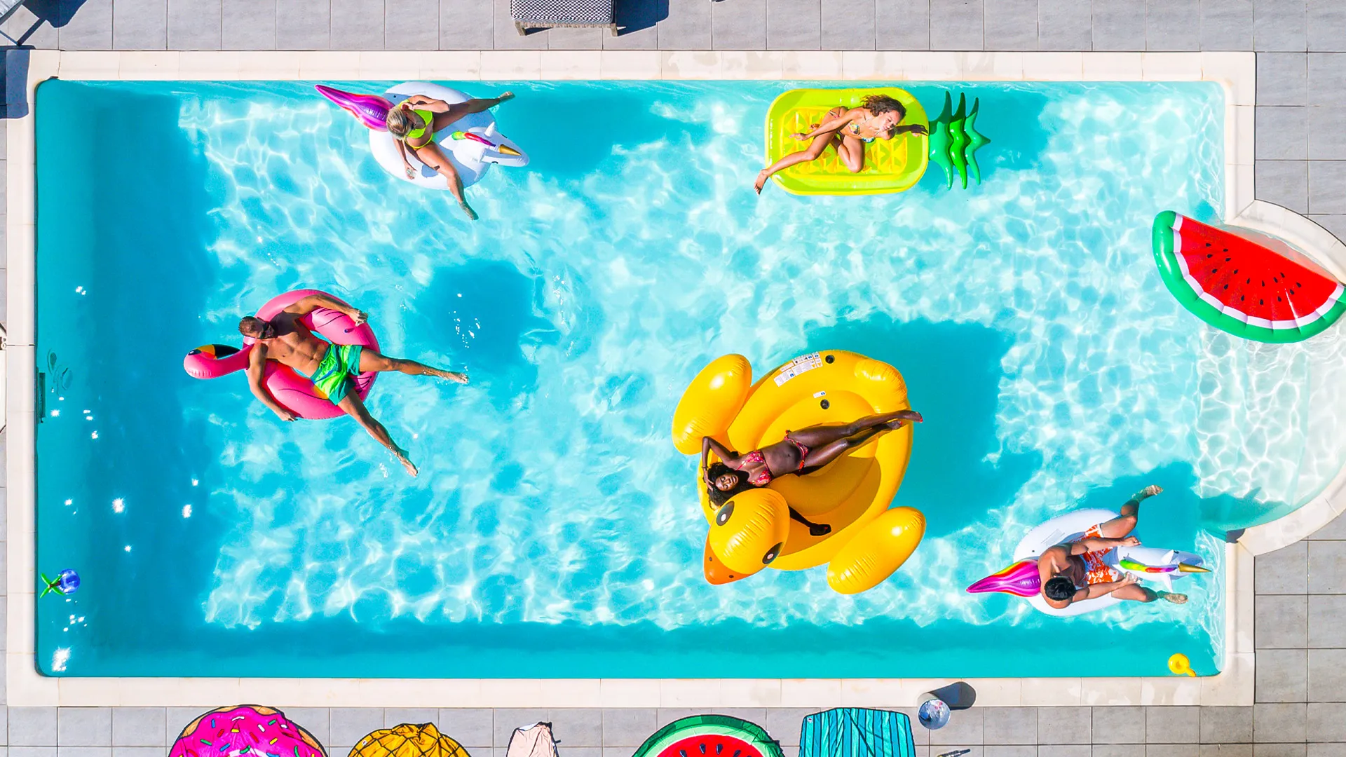 Aerial view of Oleo Cancun Playa pool party with floats, inflatables, and guests relaxing under the sun.