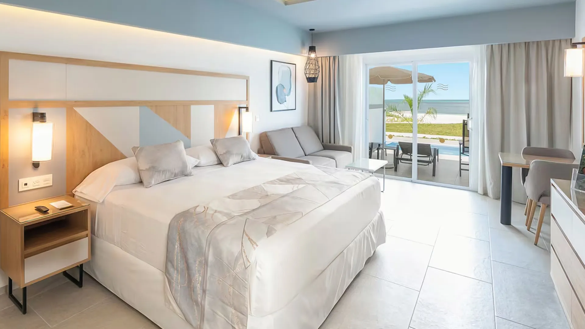 Modern ocean-view room at Riu Caribe Cancun featuring a king bed, balcony, and sea-facing terrace.