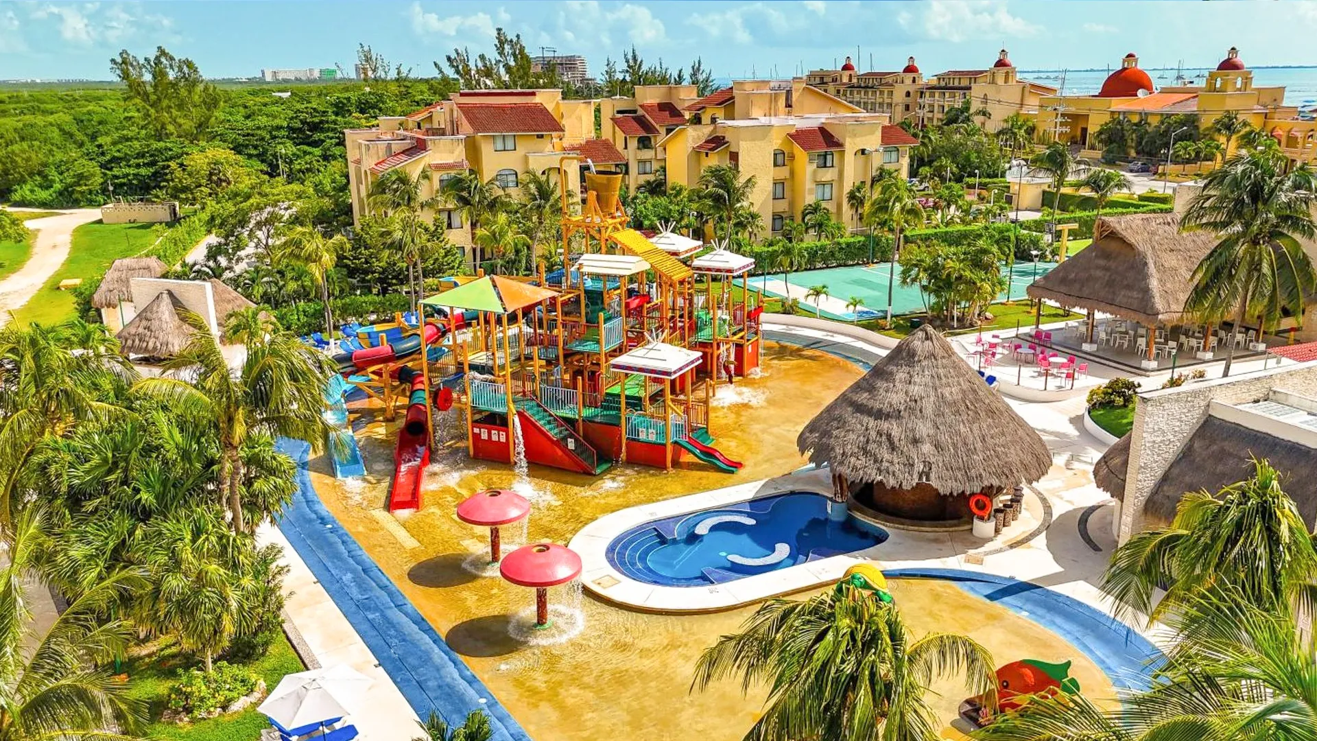 Aerial view of All Ritmo Cancun Resort & Waterpark showing colorful slides, splash pools, and tropical gardens.