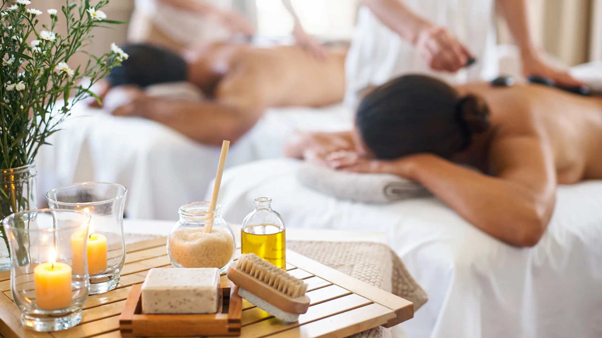 Couple receiving a relaxing couples massage in a serene spa room with candles and essential oils.
