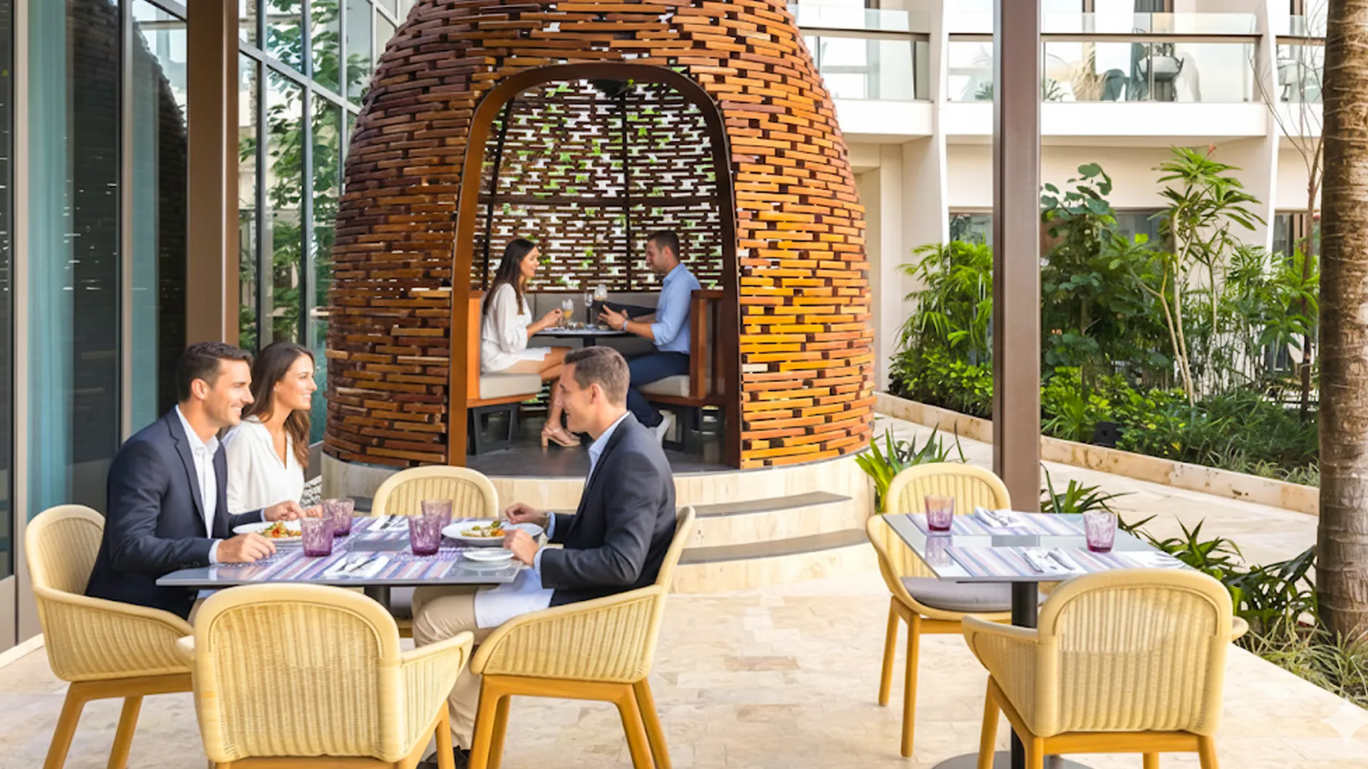 Guests dining at an elegant outdoor restaurant at Hilton Cancun with modern wood cabana design.