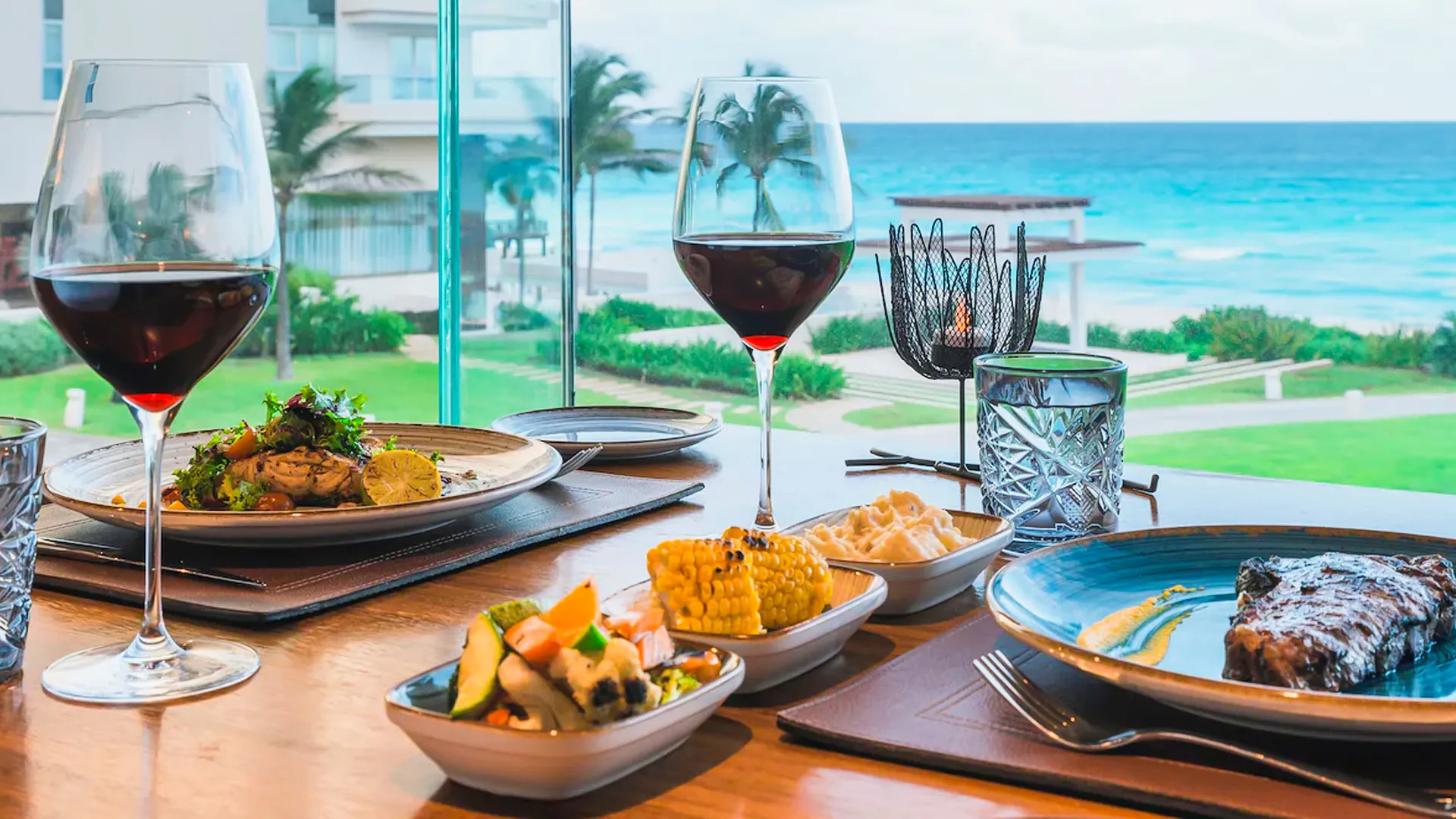 Table with wine, steak, and side dishes overlooking the Caribbean Sea at Iberostar Cancun.