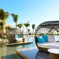 Luxury poolside cabanas with turquoise cushions at TRS Coral Hotel Cancun surrounded by palm trees and modern architecture.