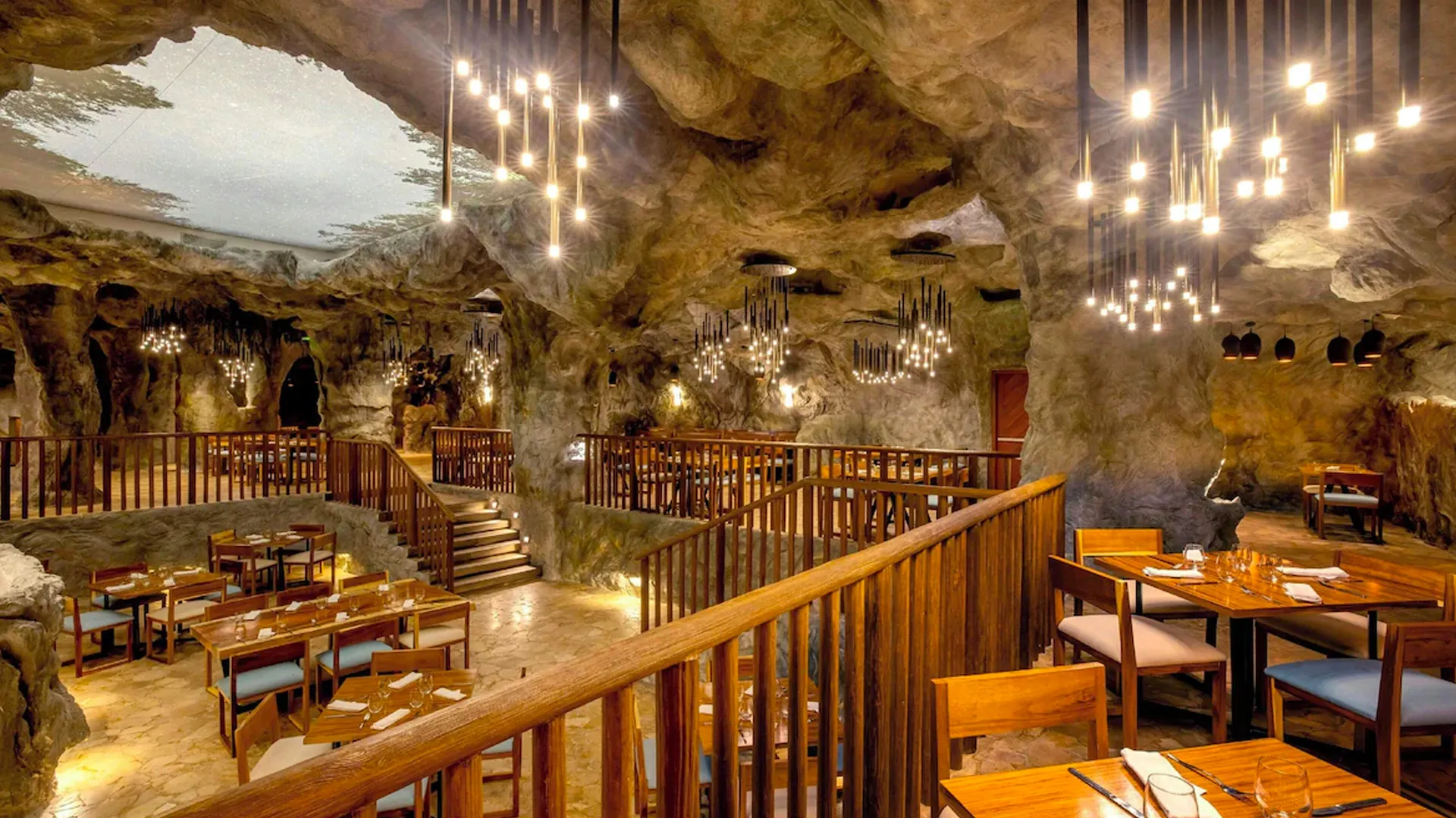 Elegant cave-style restaurant interior at Royalton Cancun with warm lighting and wooden furniture.