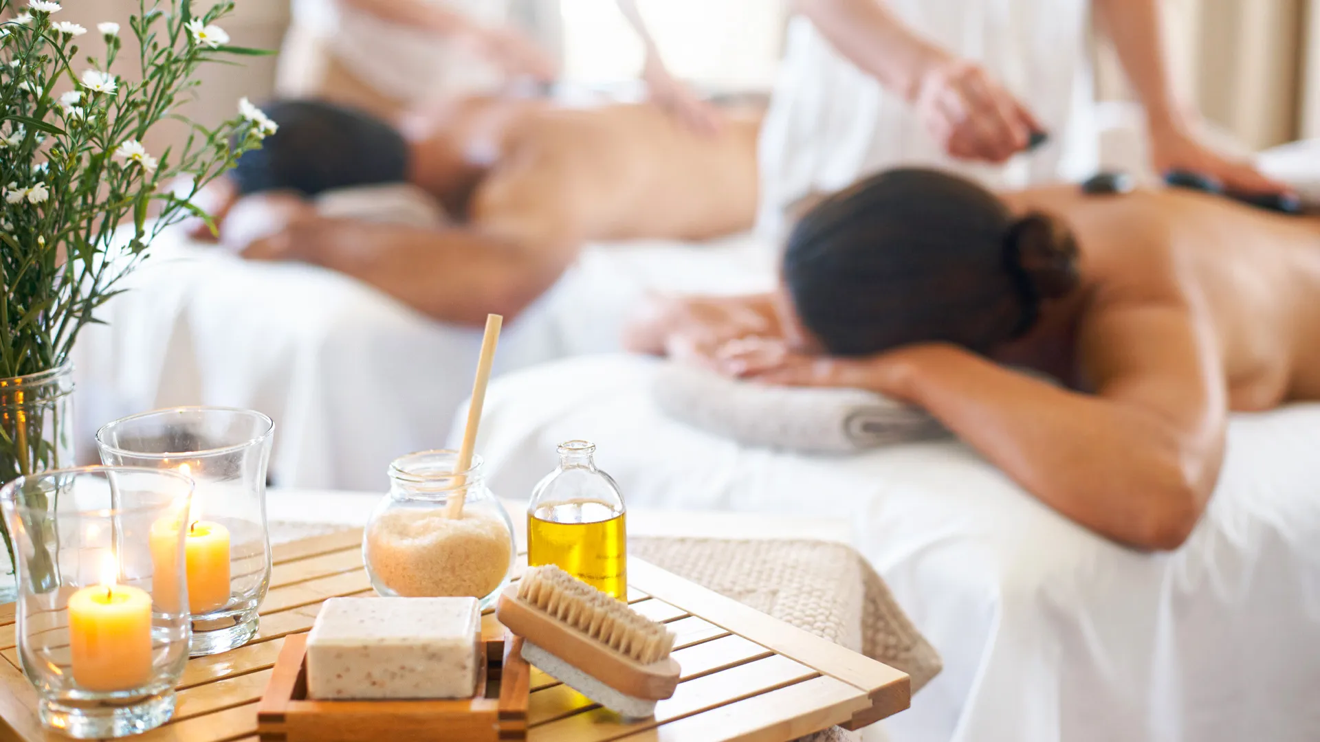 A couple receiving a spa treatment, with towels over their eyes, enjoying a relaxing moment in a beachside setting.