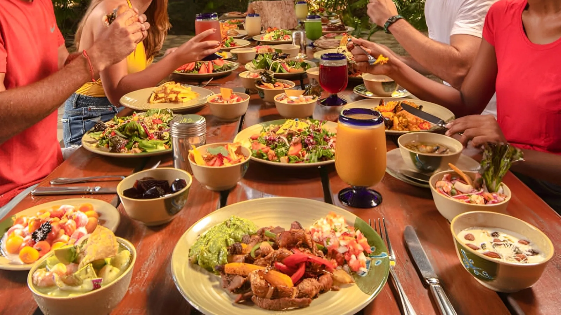 Colorful buffet table at Xplor Park with fresh salads, grilled meats, tropical fruits, and refreshing drinks