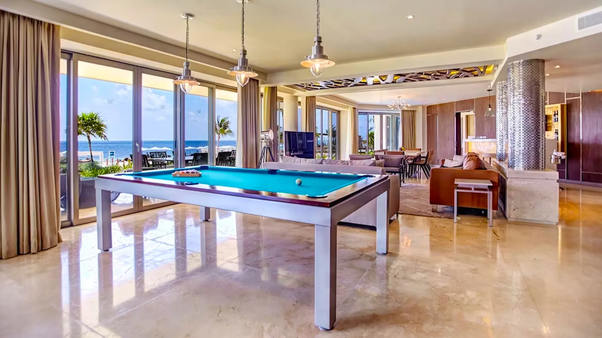 Luxury oceanfront suite at Royalton Cancun featuring a pool table, seating area, and panoramic sea views.