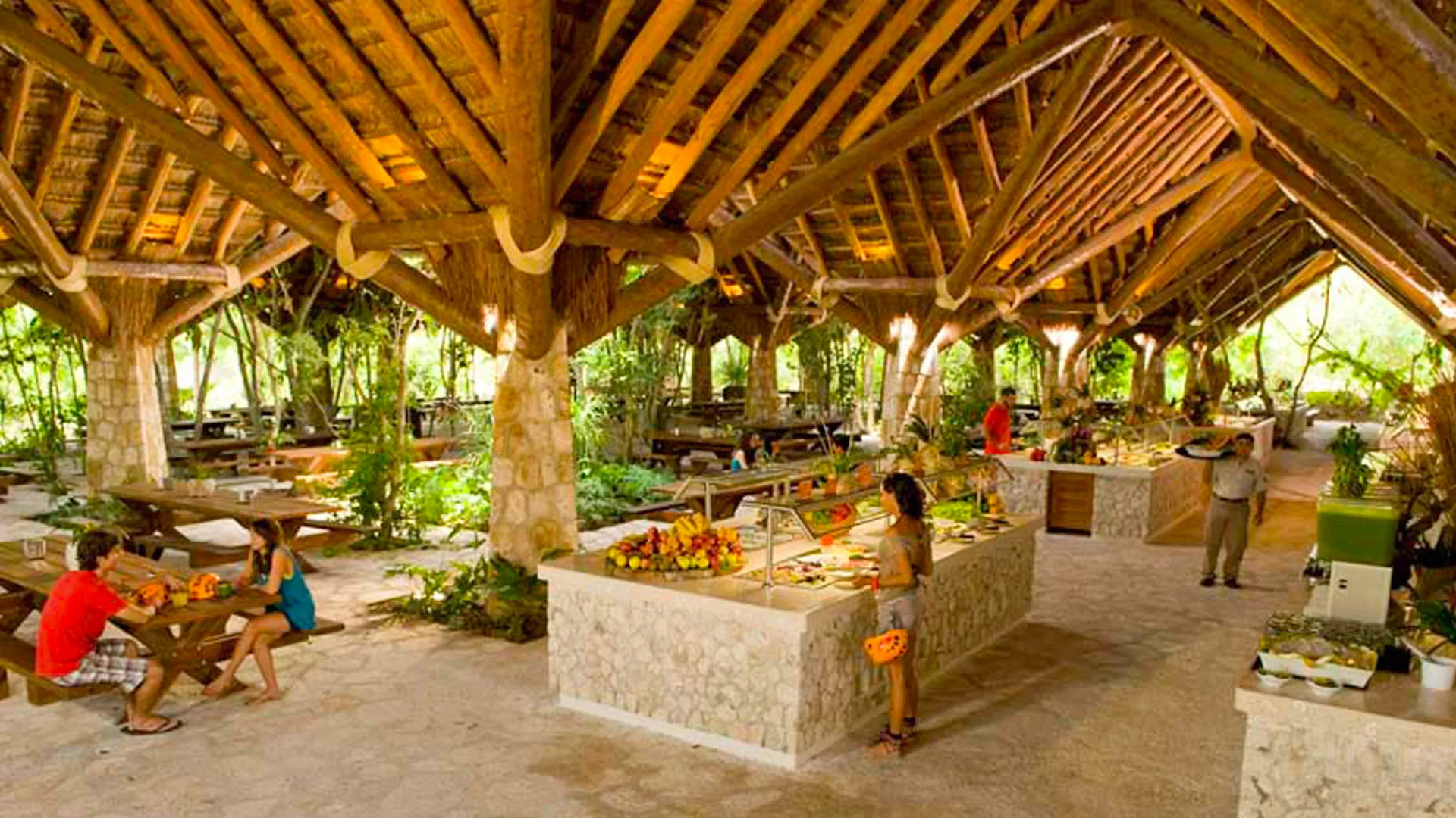 Open-air restaurant at Xplor Park with wooden beams, stone counters, and natural jungle surroundings.