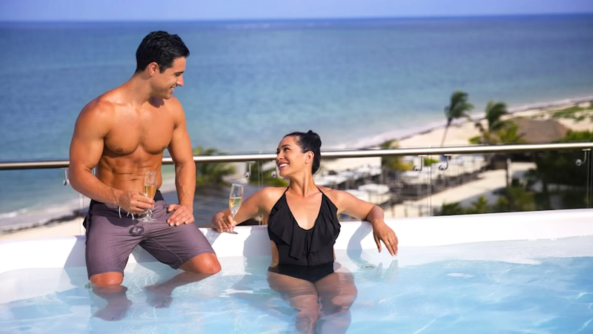 Couple enjoying champagne in rooftop Jacuzzi with ocean view at Royalton Cancun Resort.