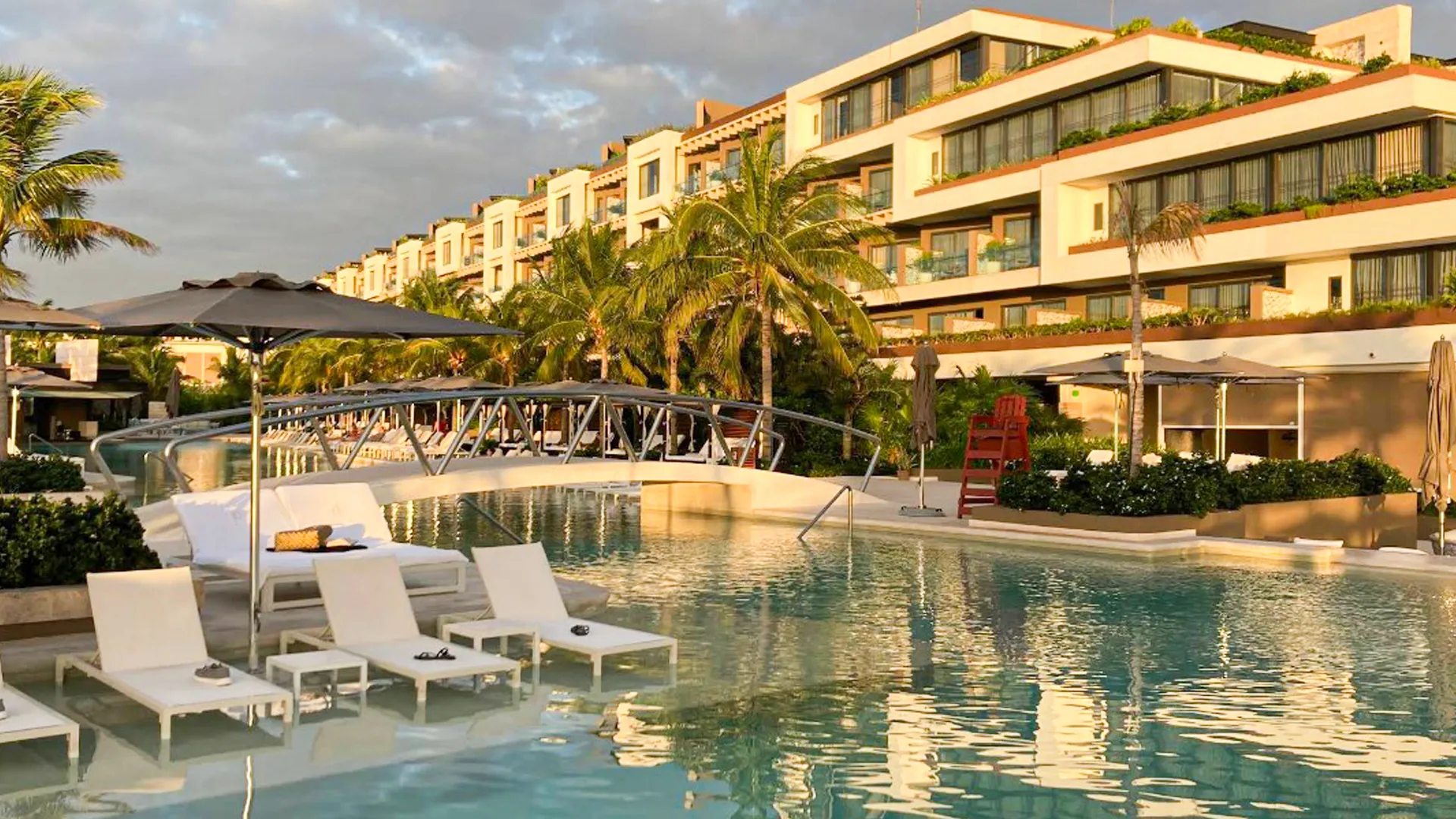 A serene pool area at Atelier Hotel with lounge chairs and a modern design, surrounded by lush palm trees.