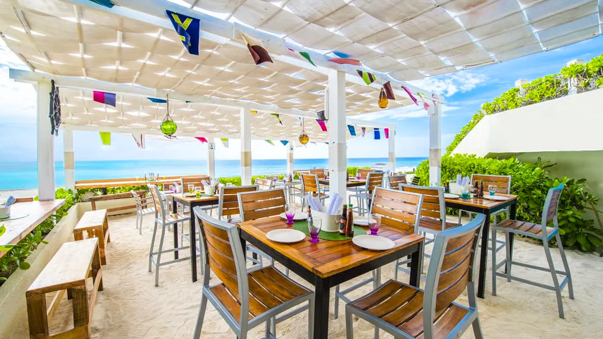 Indoor dining area at an unnamed resort with wooden tables, teal cushioned chairs, a family of three eating, and warm lighting with orange accents.
