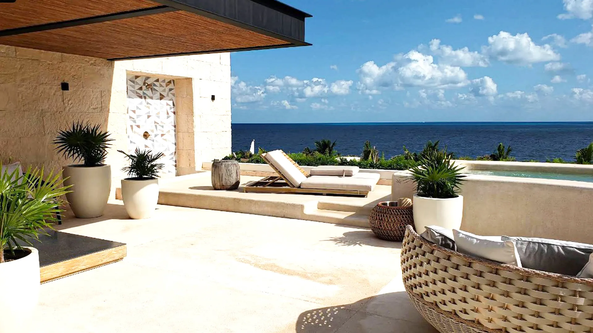 A stunning ocean view from a private terrace at Atelier Playa Mujeres, featuring lounge chairs and tropical plants with a serene and relaxing atmosphere.