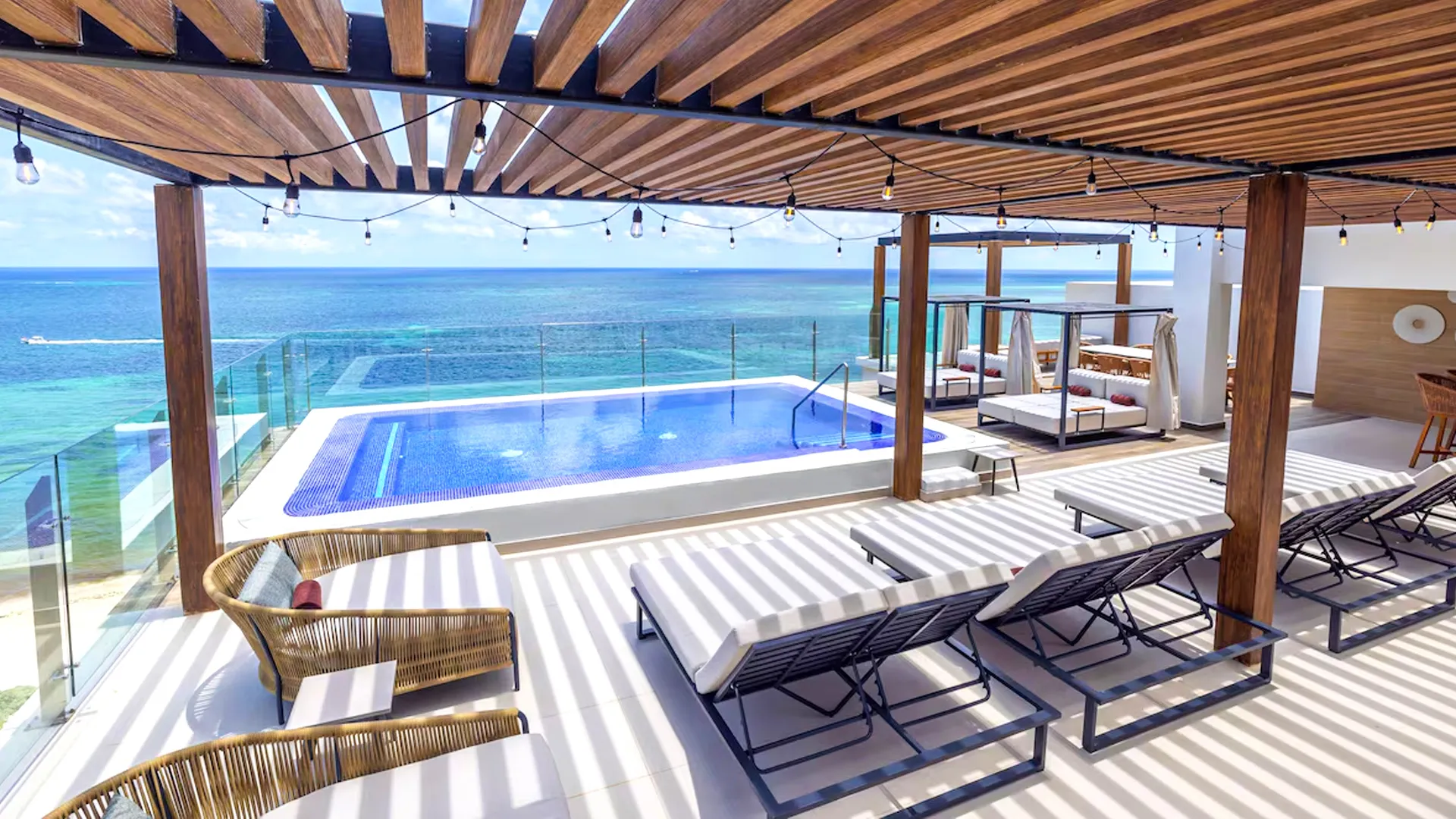 Rooftop infinity pool with ocean view, lounge chairs, and wooden pergola at Royalton Cancun.