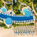 Aerial view of Live Aqua Cancun Resort featuring curved infinity pools, blue umbrellas, and beachfront cabanas along the white sands of the Caribbean Sea.