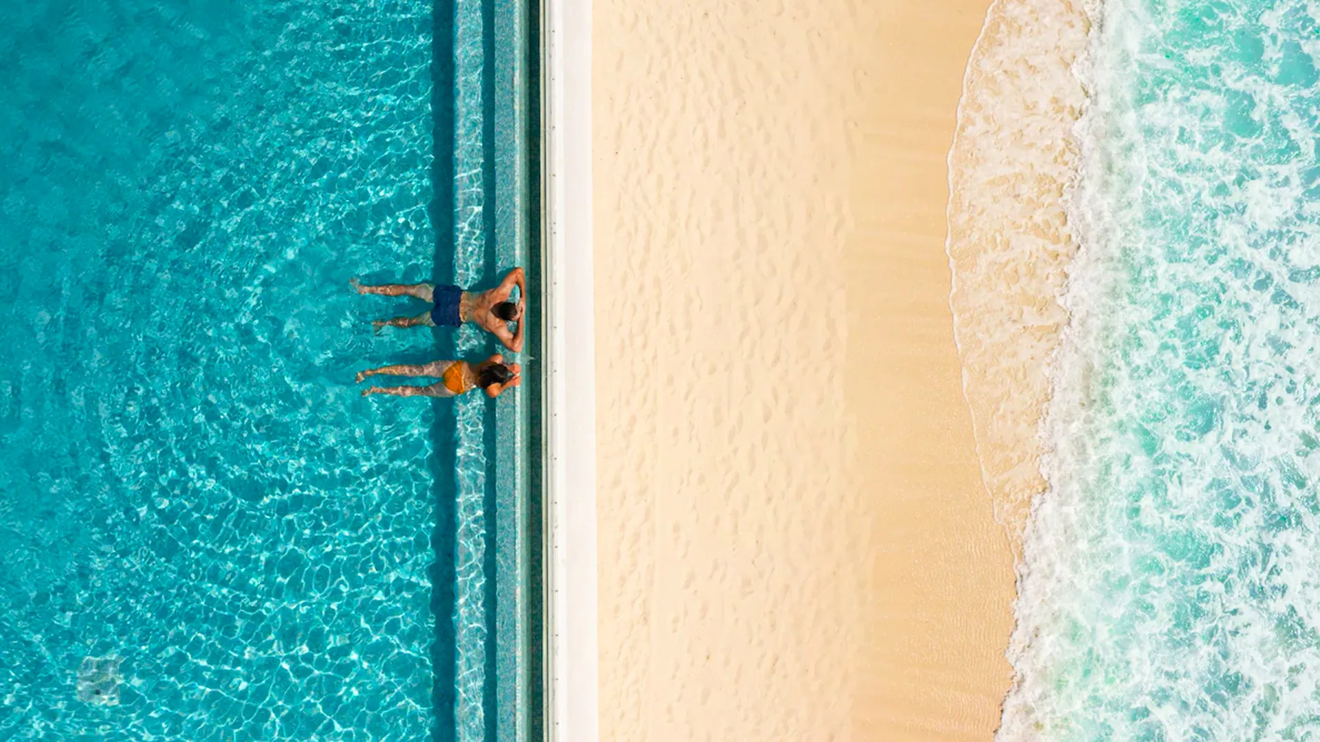 A couple enjoying the water, floating side by side, experiencing the perfect beach conditions at Sun Palace Cancun.