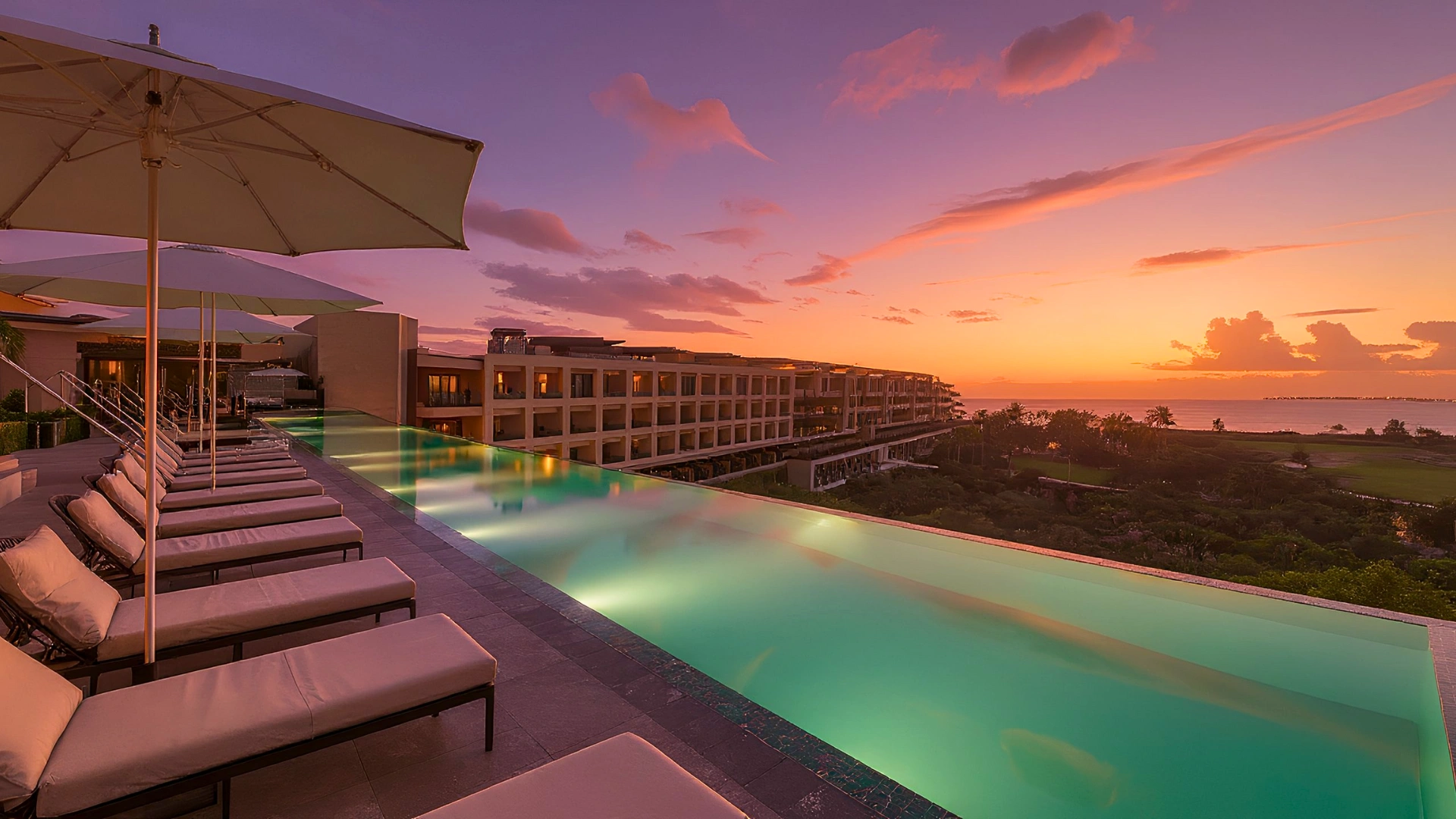 A peaceful view of the luxury pool area at Atelier Playa Mujeres, featuring lounge chairs and umbrellas.