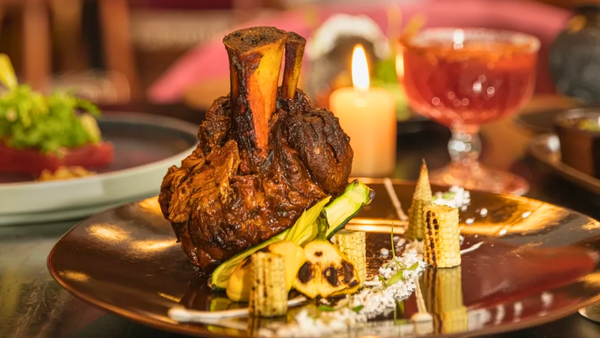 Close-up of a gourmet beef shank dish served at Hilton Cancun All-Inclusive Resort restaurant, with elegant plating and warm candlelit background.